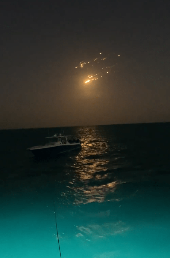 Boat at night with fireworks in the sky.