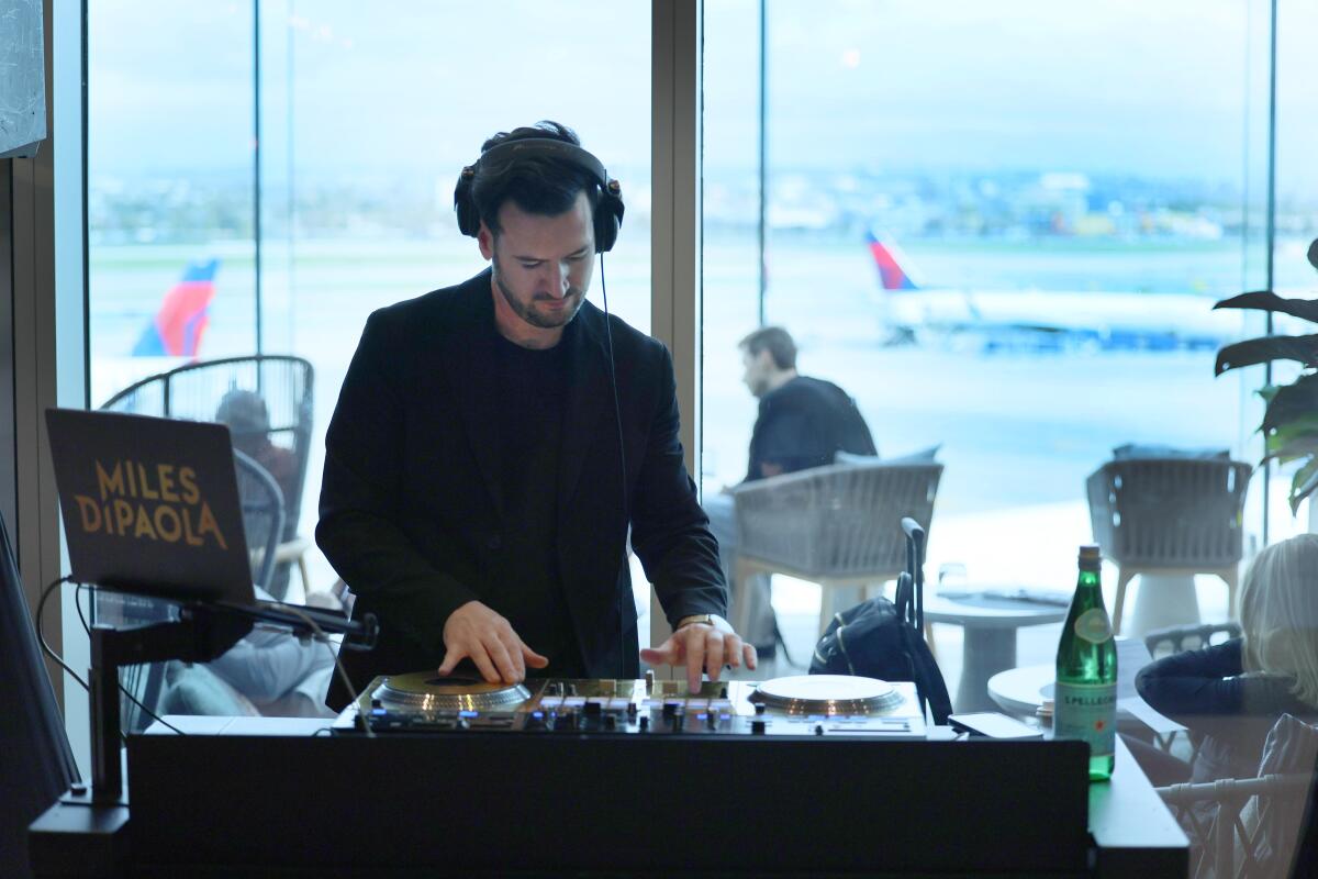 A DJ performs in the LAX-Delta One lounge space, a premium offering that serves the company and its customers. 