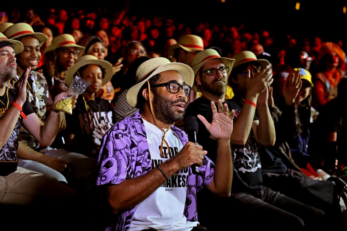 Matt Owens, in glasses and a straw hat, sits in a movie theater.