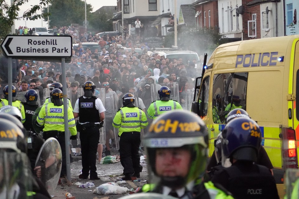 Riot police in Southport, England, face a large crowd of protesters.