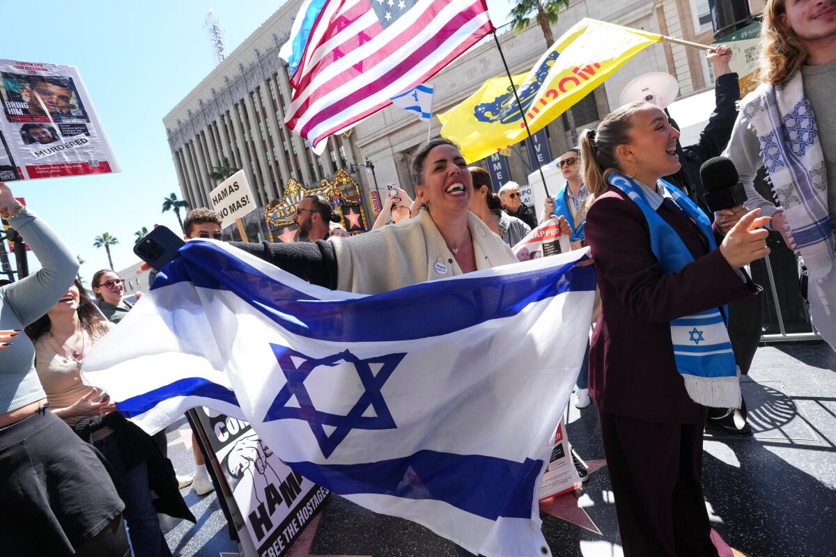 Demonstrators hold signs and flags referencing the Israel-Hamas war along the Hollywood Walk of Fame.