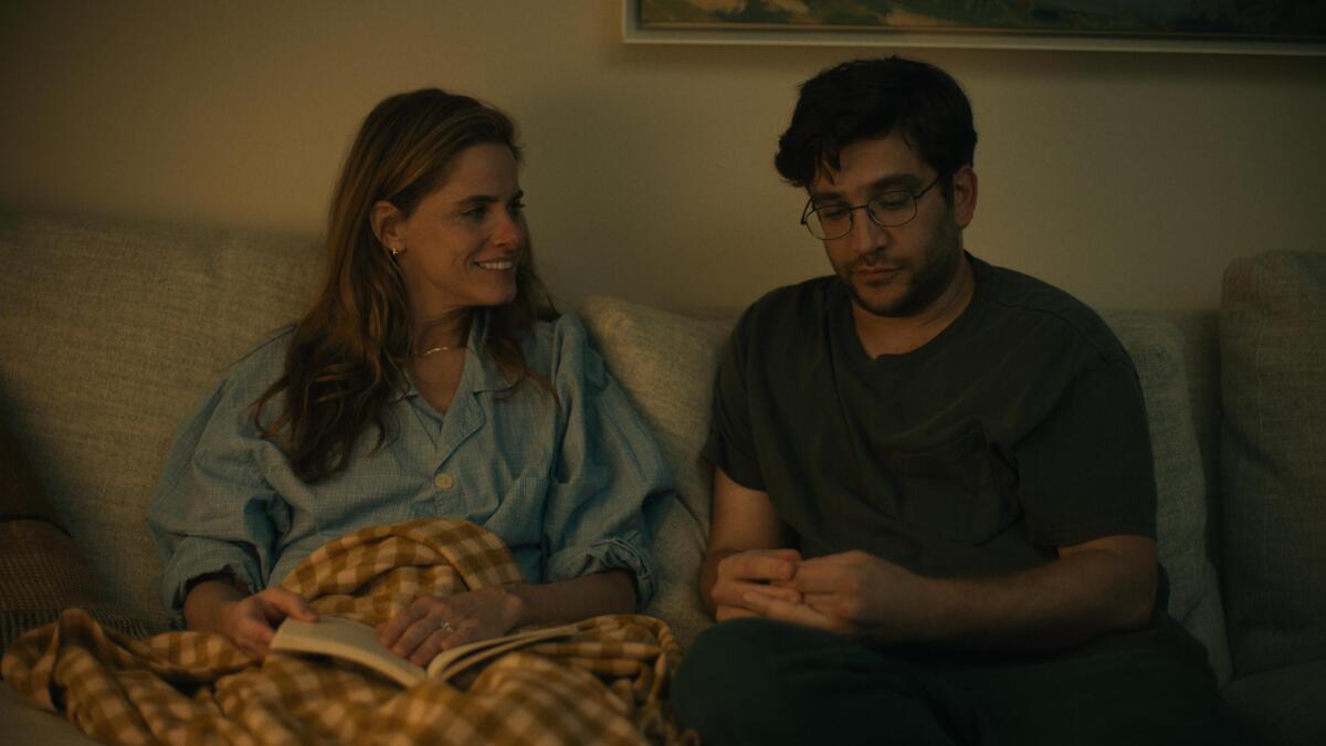 A woman looks at the man sitting next to her on a couch