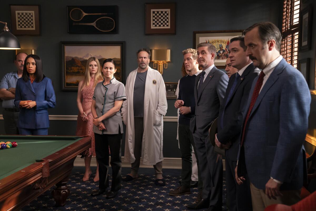 A group of people standing around a pool table in a game room.