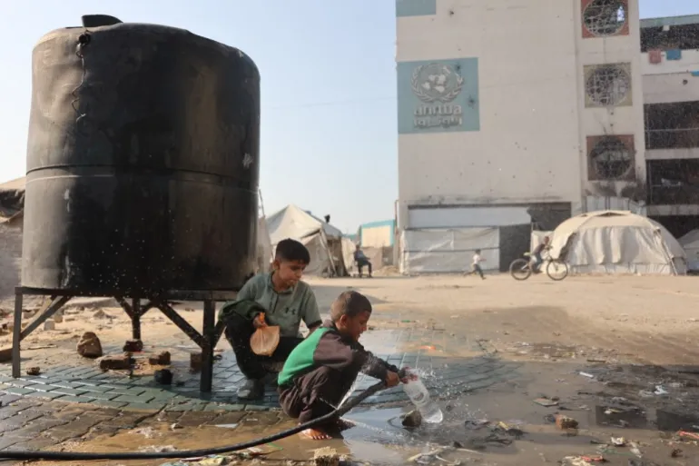 A boy fills a plastic bottle with water inside a camp for displaced Palestinians at a school-turned-shelter in Al-Rimal neighbourhood of Gaza City on November 5, 2025. [File: Omar Al Qattaa]