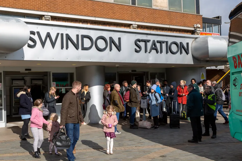 People waiting for a rail replacement bus service at Swindon Station in Wiltshire, England.