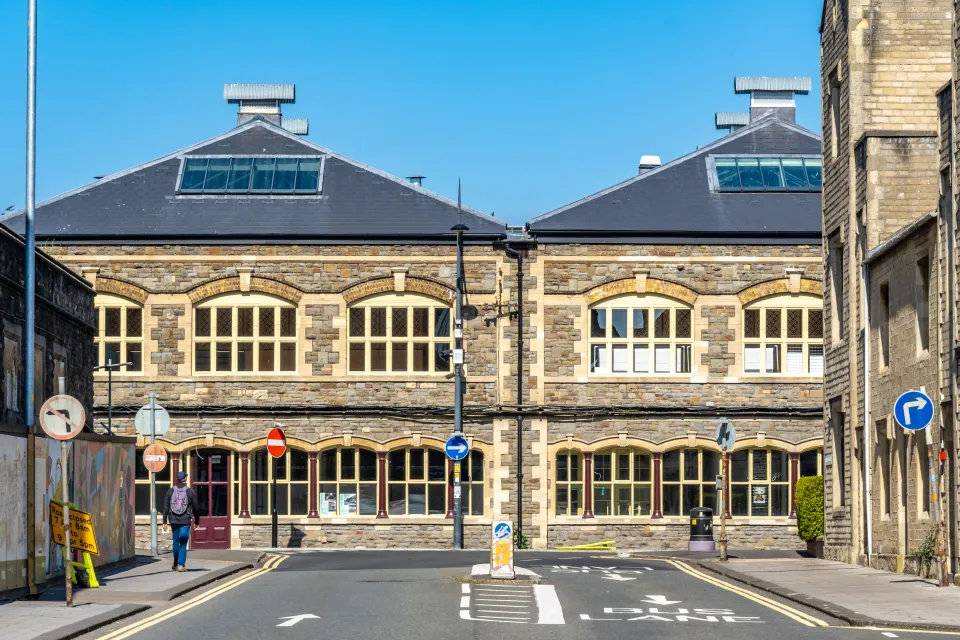 Man walks toward historic railway buildings in Swindon.