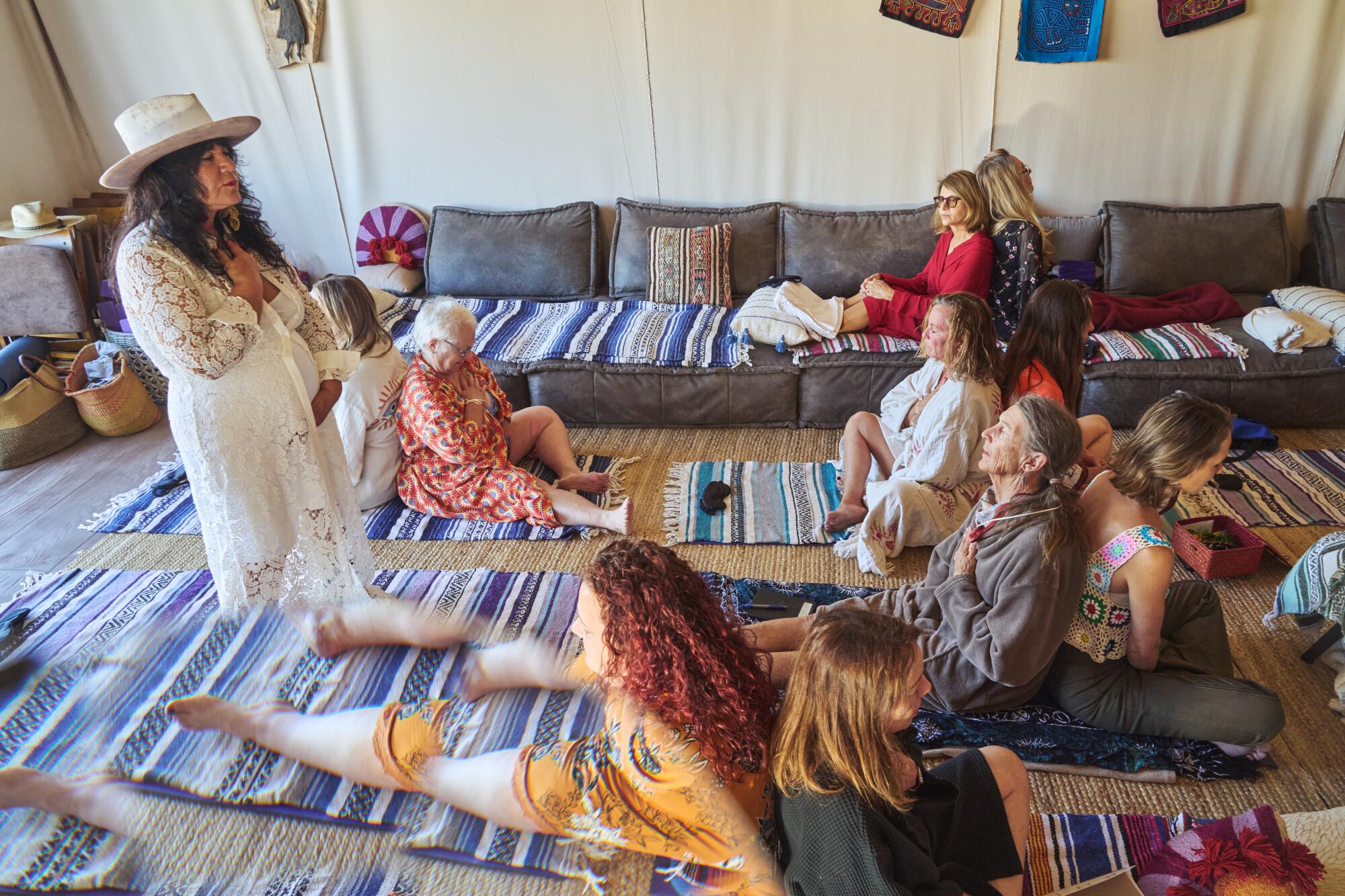 Women sit on the floor, back to back, during a guided meditation.