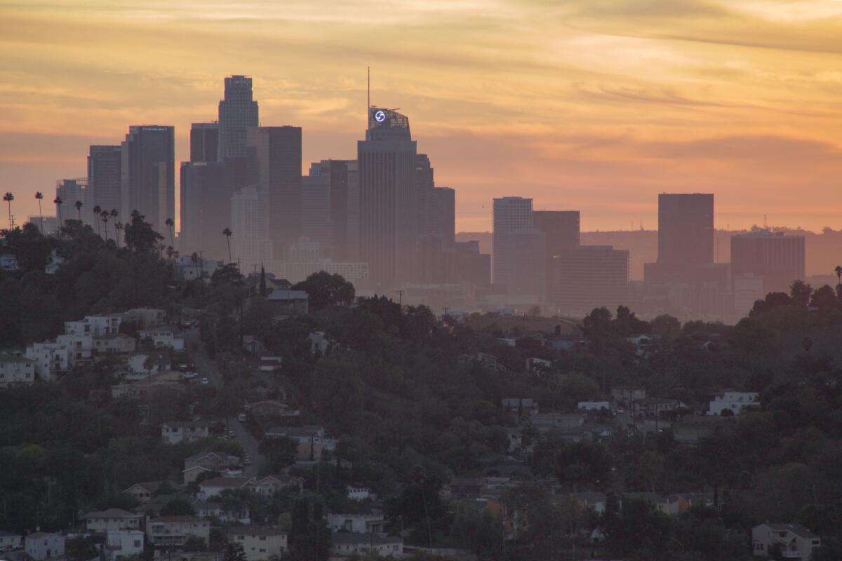 Skyscrapers in the distance lit by a pinkish orange sunset.