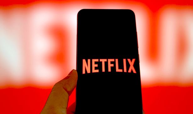 A person holds a phone with the Netflix logo on it