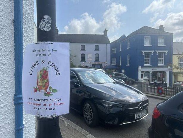 A sign on a lamppost advertises a 'hymns and Pimms' night at a local church