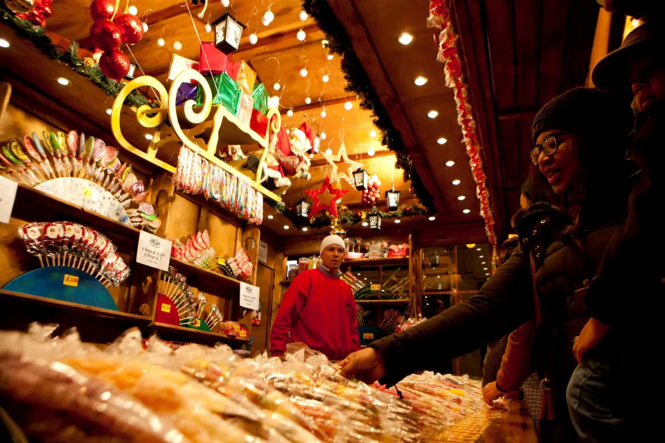 A woman choosing candy at a Christmas market stall.