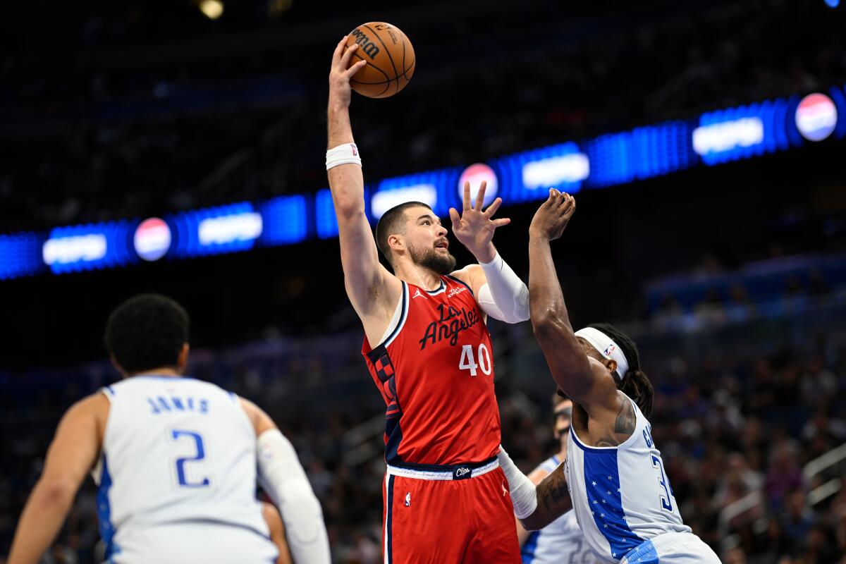 Clippers center Ivica Zubac, center, shoots a short-range shot between Orlando's Tyus Jones, left, and Wendell Carter Jr.