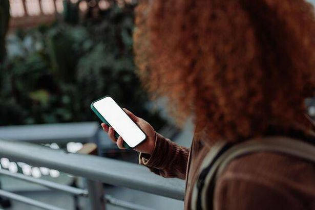 Tourist using smart phone with empty screen at airport or mall