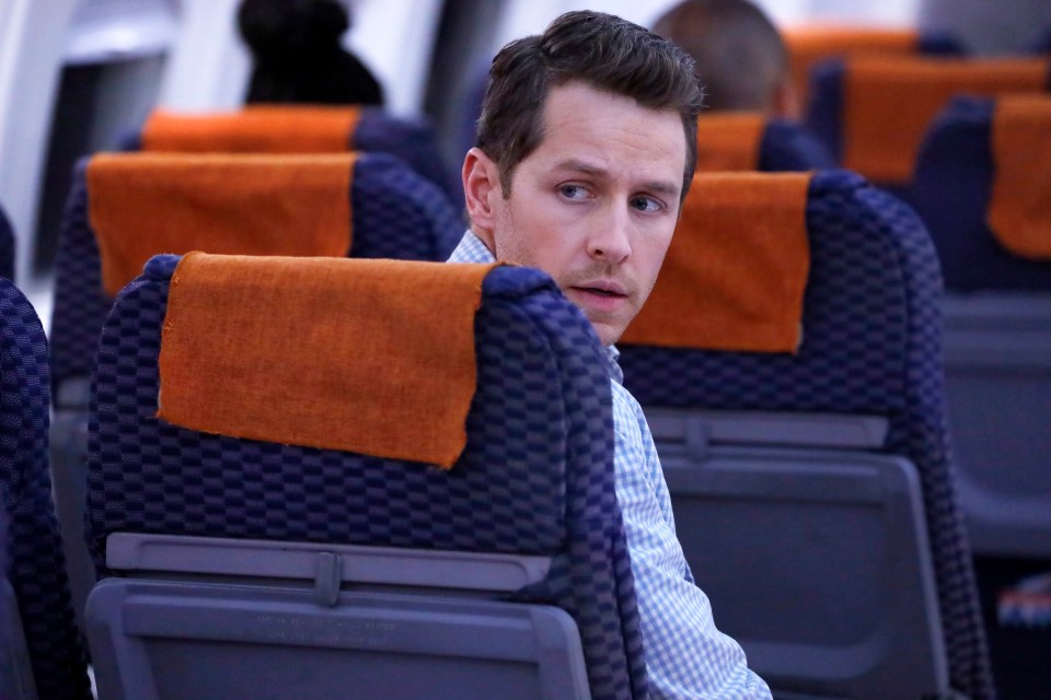 Josh Dallas as Ben Stone on "Manifest" looking over his shoulder while seated on an airplane.