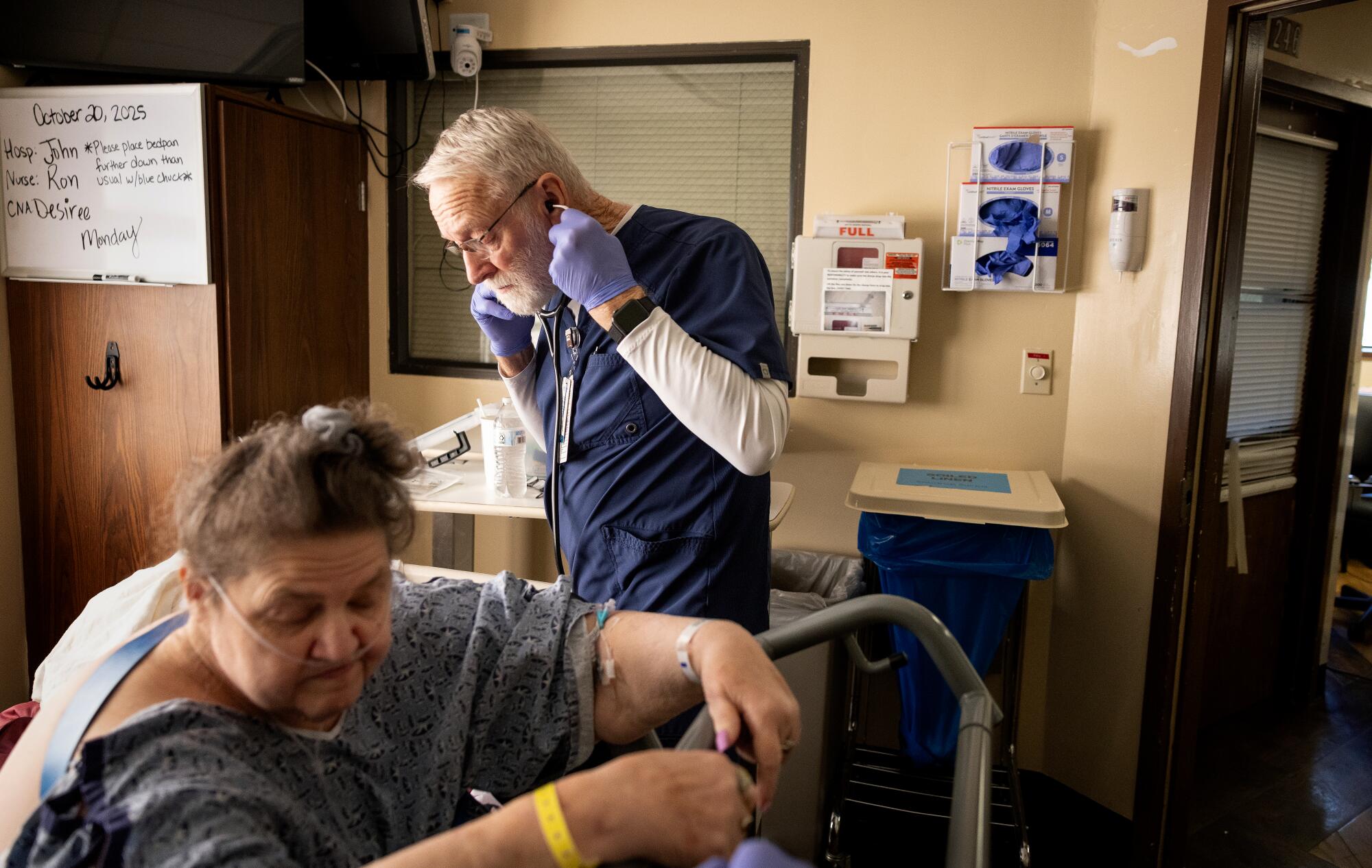 A nurse checks on a patient using a stethoscope