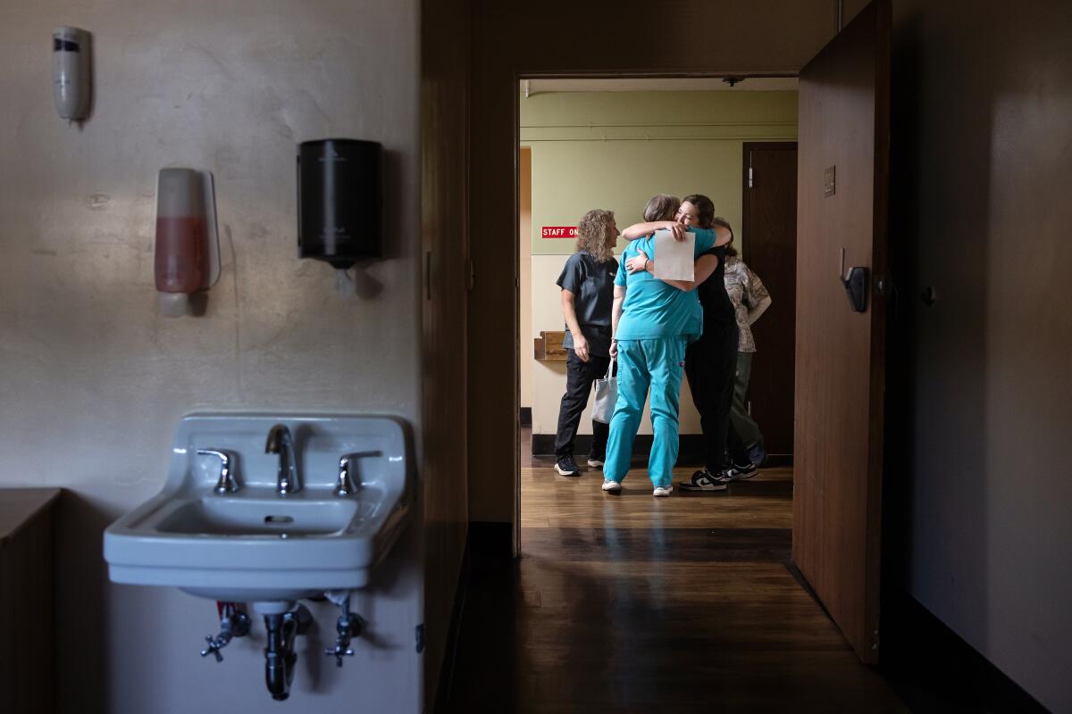 Medical assistant Kylee Lutz, 26, right, hugs activities coordinator Rita Robledo on closing day. Lutz, who will continue to work in the clinic that remains open, said through tears, "It's not going to be the same without you ladies."
