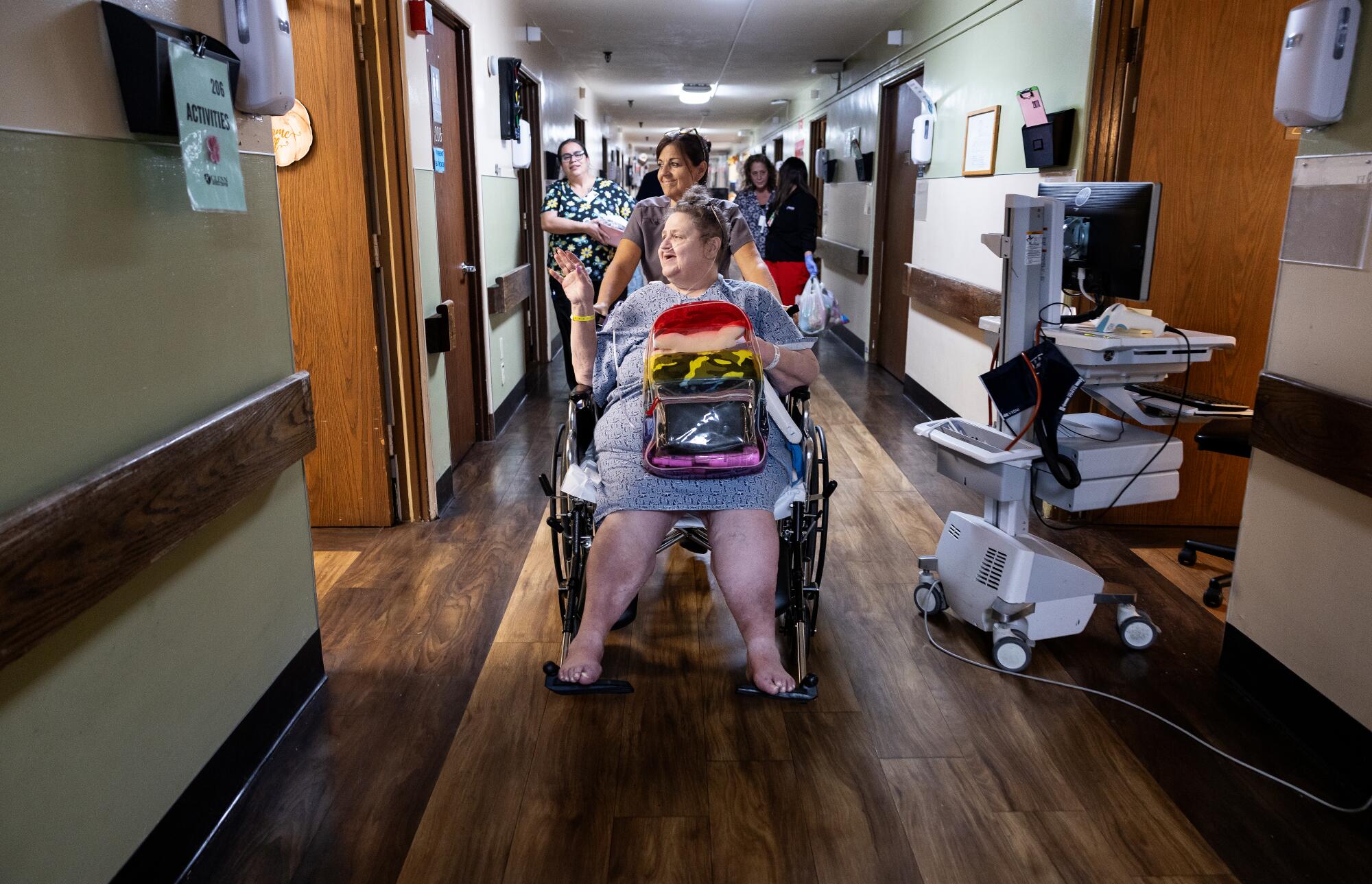 Helena Griffith, 62, one of the last patients, waves goodbye as patient transport Jolene Guerra pushes her wheelchair