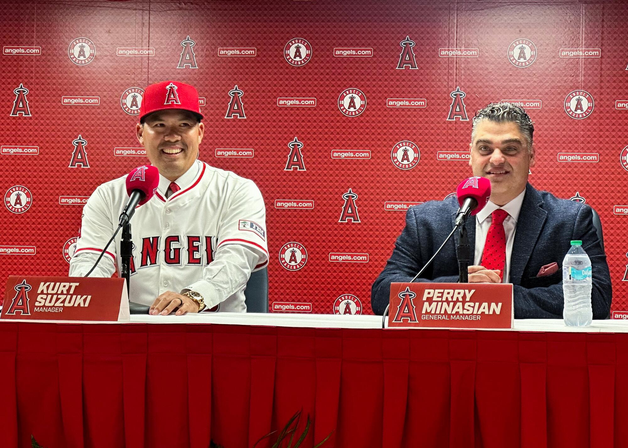 New Angels manager Kurt Suzuki, left, and general manager Perry Minasian speak to reporters at Angel Stadium last month.