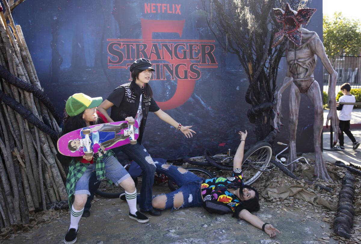 People pose for a photograph with a "Stranger Things" backdrop.