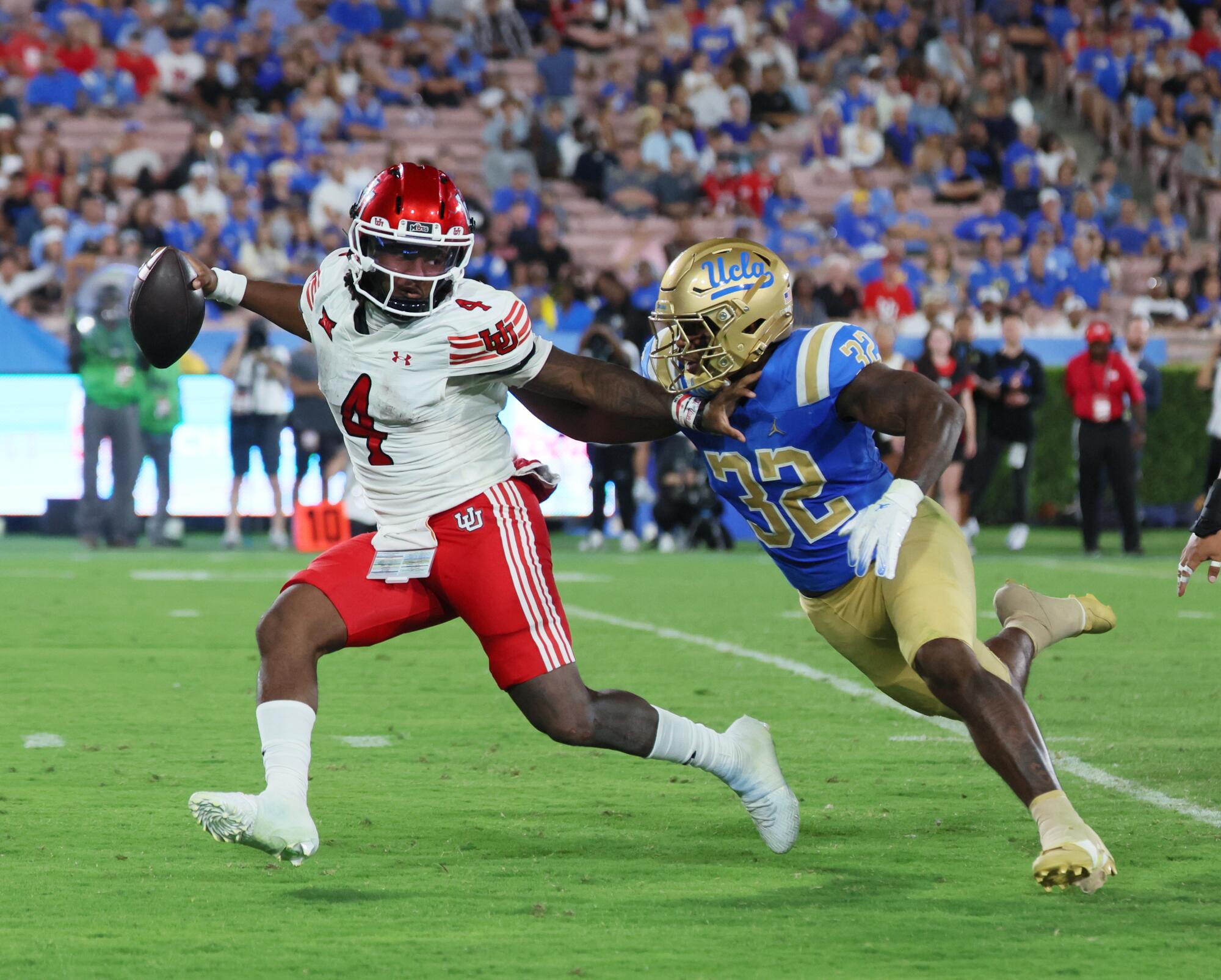 Utah quarterback Devon Dampier (4) holds the ball and pushes Bruins linebacker Isaiah Chisom (32) on Aug. 30.
