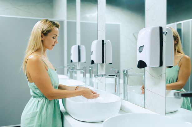 Woman washes her hands in a public bathroom