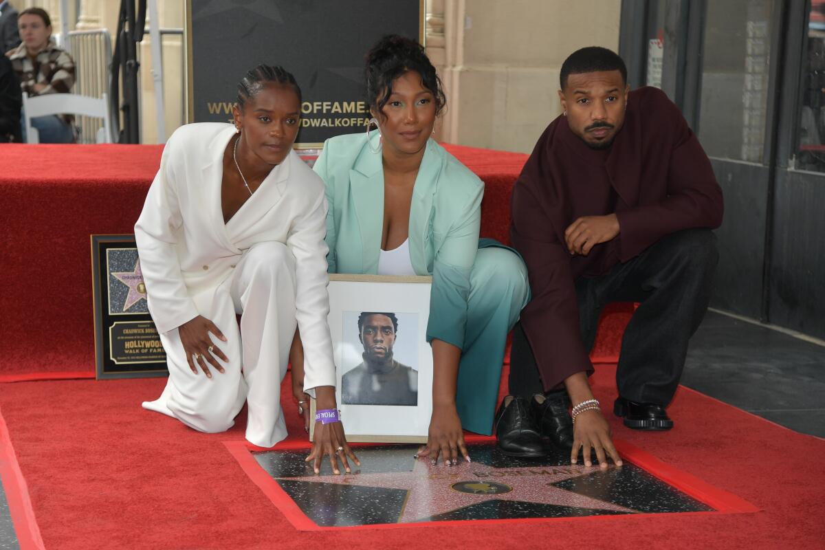 Letitia Wright, Simone Ledward Boseman and Michael B. Jordan kneel on Hollywood Walk of Fame, each with a hand on a new star