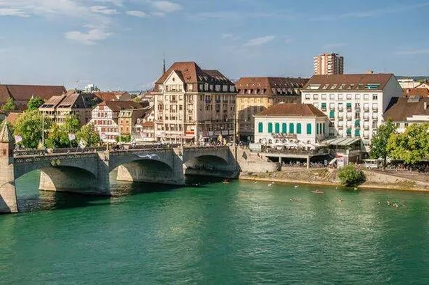 Close-up aerial view of the quays of the river Rhine in the city center of Basel, with a view on people swimming in its turquoise colored waters, the