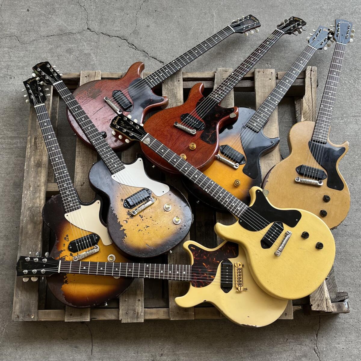 A pile of guitars on a wood pallet.