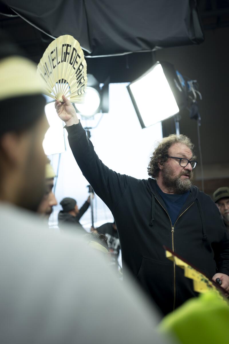 A man in a black hoodie holding up a white fan.