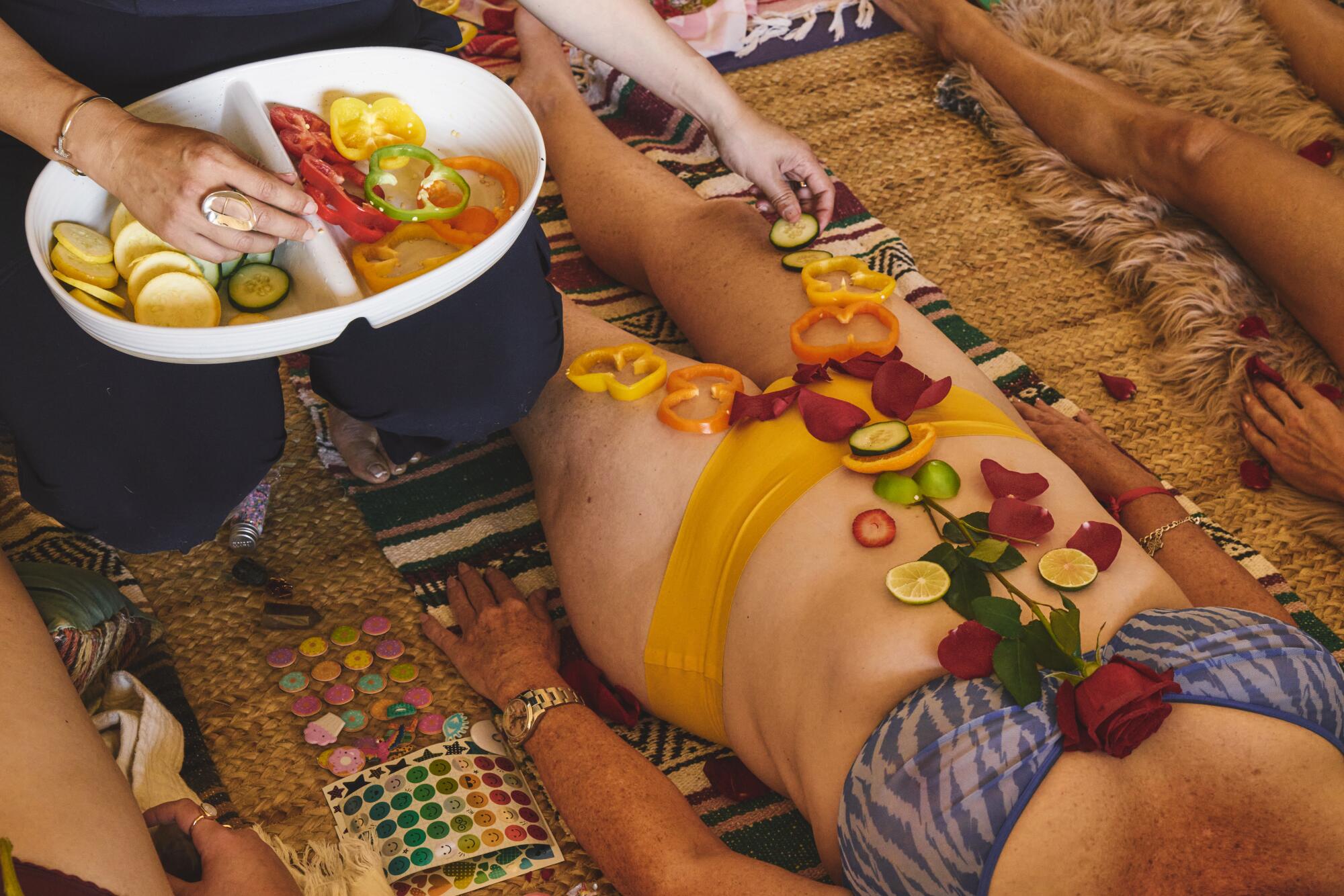 Fresh fruit, vegetables and flowers are placed on a female body.