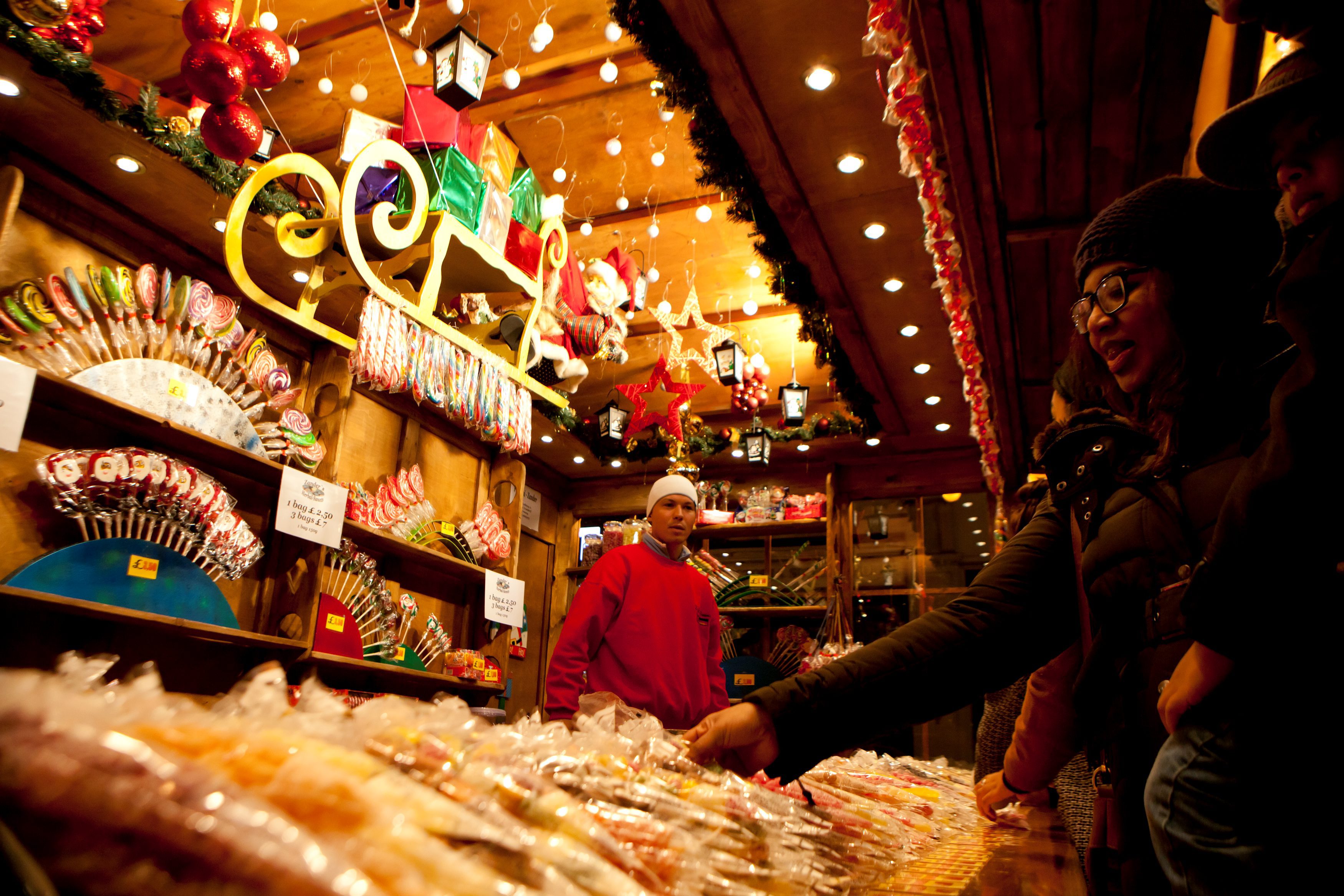 A woman choosing candy at a Christmas market stall.