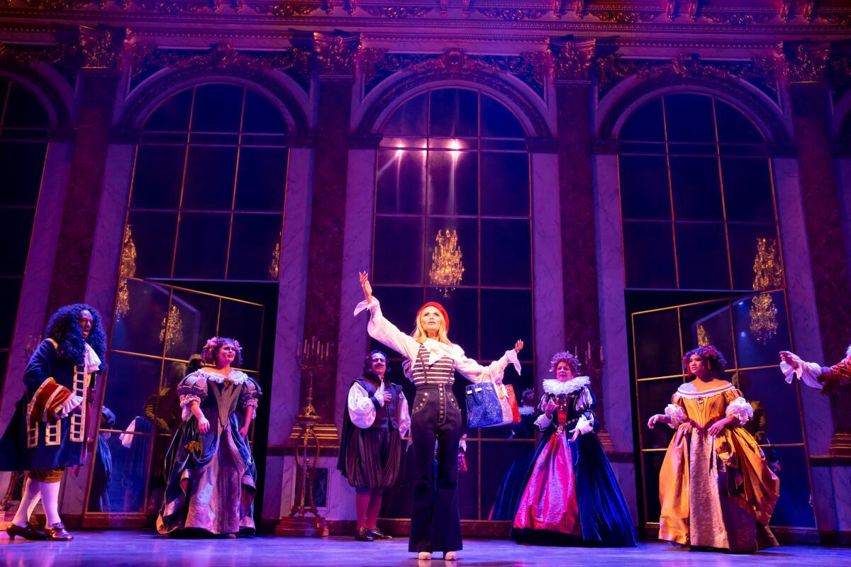 Kristin Chenoweth and the Company of "The Queen of Versailles," many in period ball gowns in a stately room.