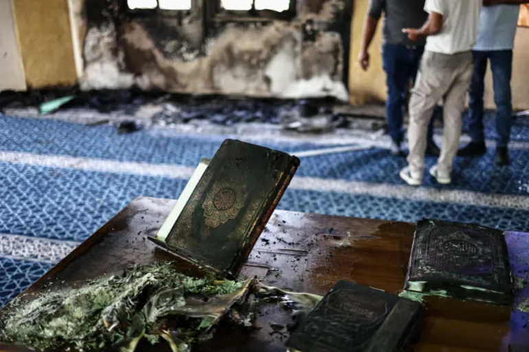 Palestinians stand next to scorched copies of the Koran inside in the Hajja Hamida Mosque after it was reportedly set on fire and vandalised by Israeli settlers in the Palestinian village of Deir Istiya, near Salfit in the Israeli-occupied West Bank, on November 13, 2025.