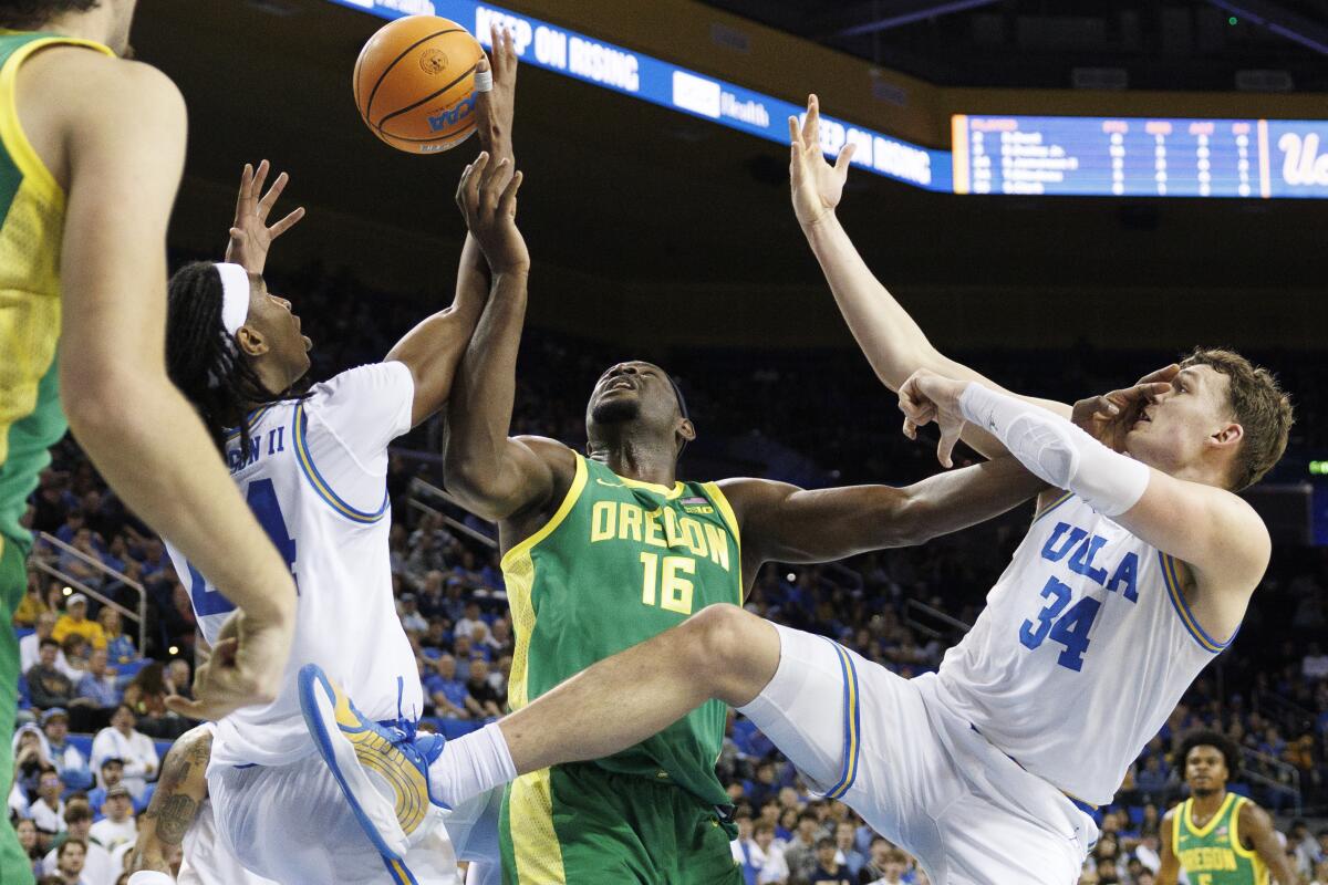 Oregon center Ege Demir (16) puts a hand to the face of UCLA forward Tyler Bilodeau while battling for a rebound.