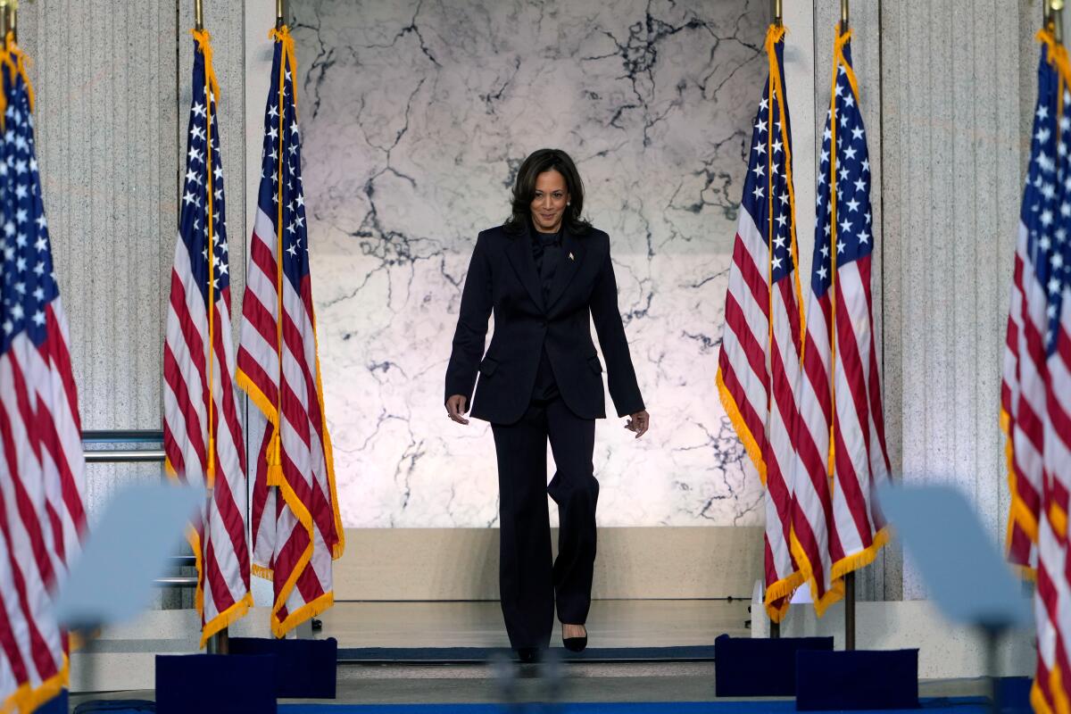 Vice President Kamala Harris walks past rows for furled American flags ahead of her 2024 concession speech