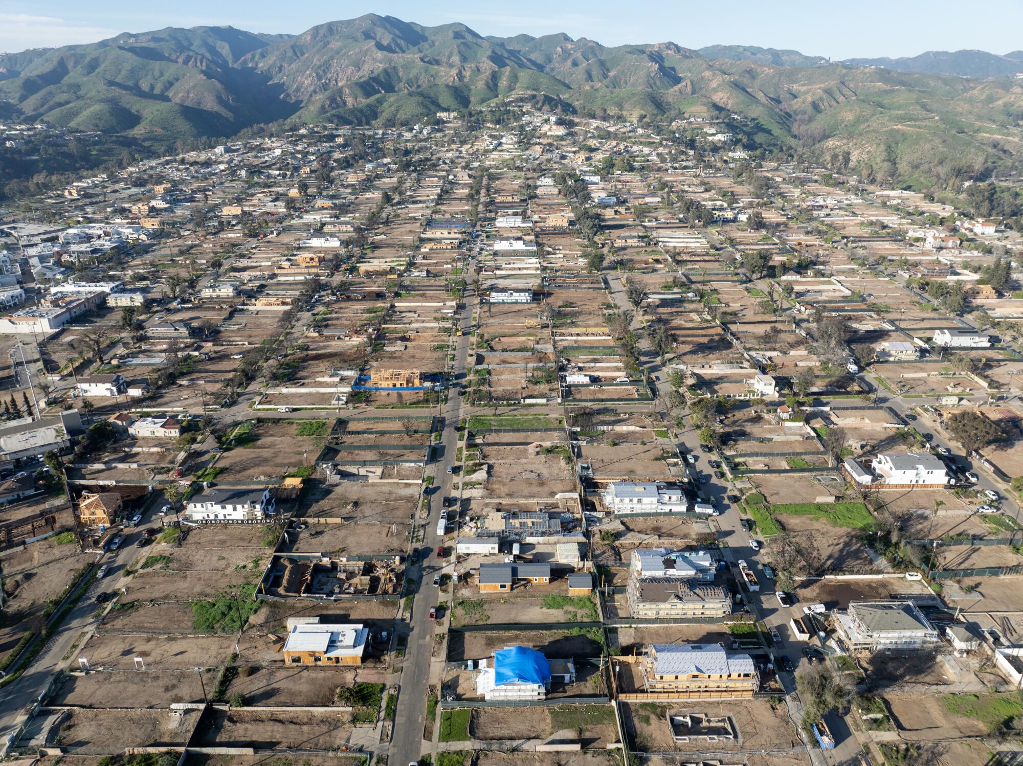 An aerial image of some homes being reconstructed and lots that remain empty in Pacific Palisades.