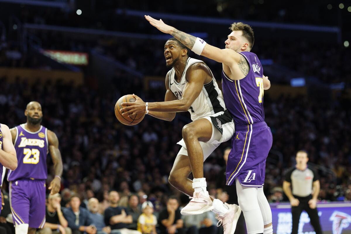 Spurs guard De'Aaron Fox, left, glides past Lakers guard Luka Doncic, right, for a layup Wednesday.