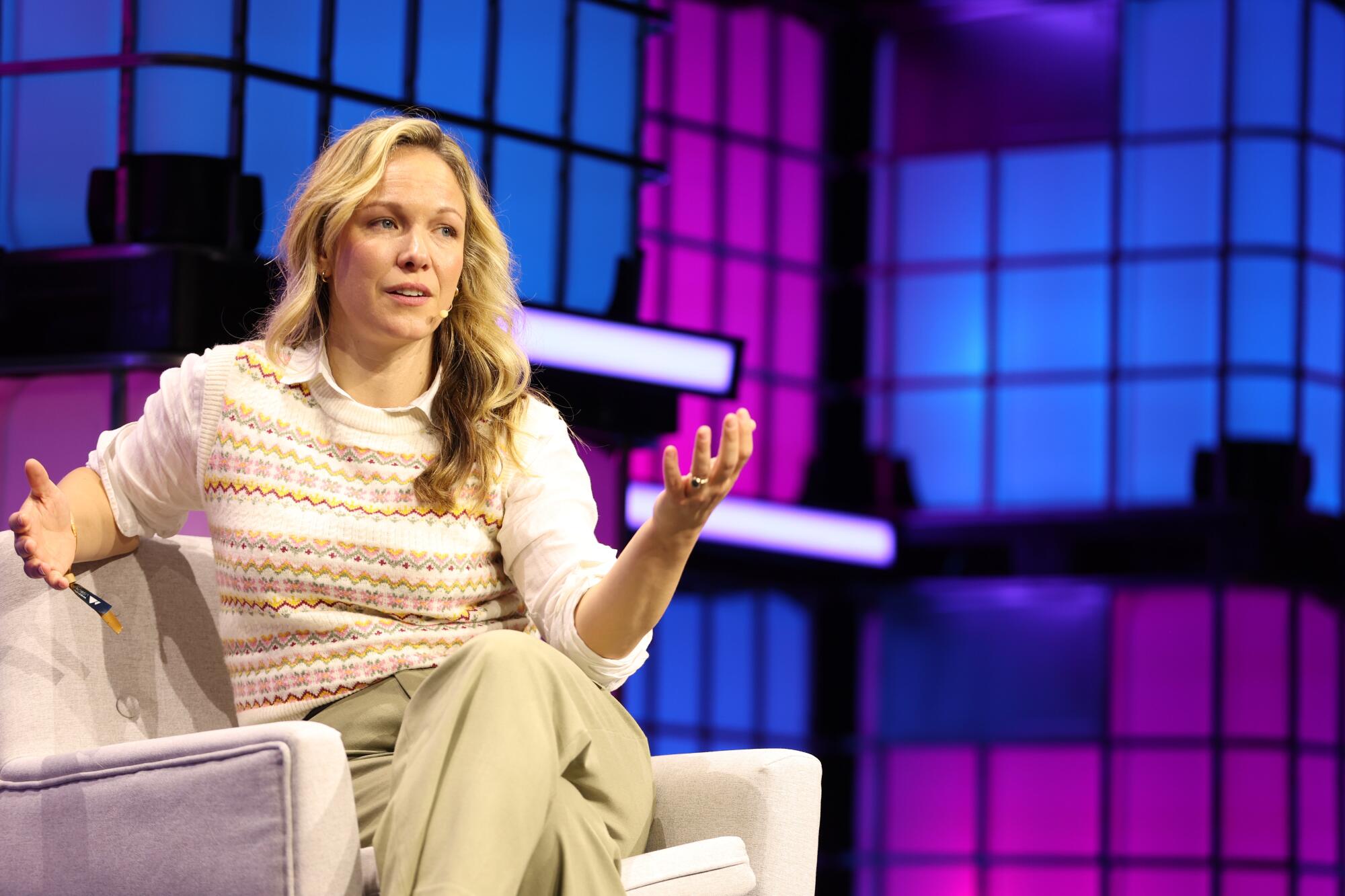 a woman sits on a couch gesturing
