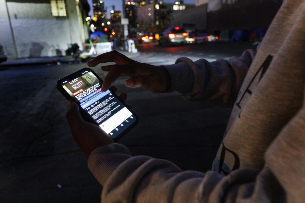 A man holds up his phone showing an ad 