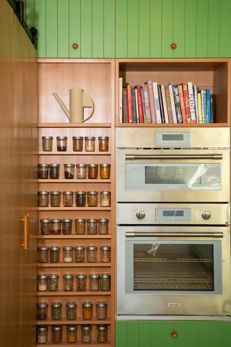 A wall of spices and an over in a kitchen.