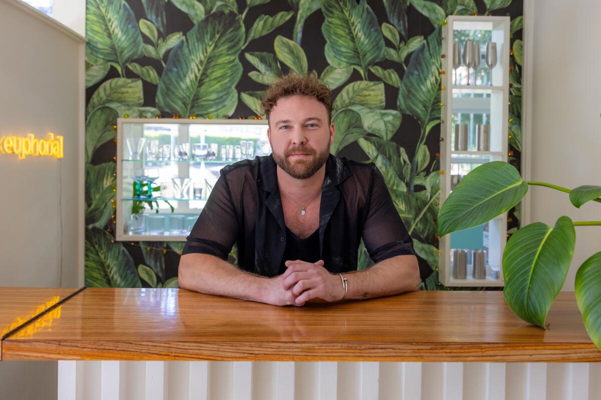 Tyler Piña stands at his bar in his penthouse apartment in the Sunset Lanai Apartments.