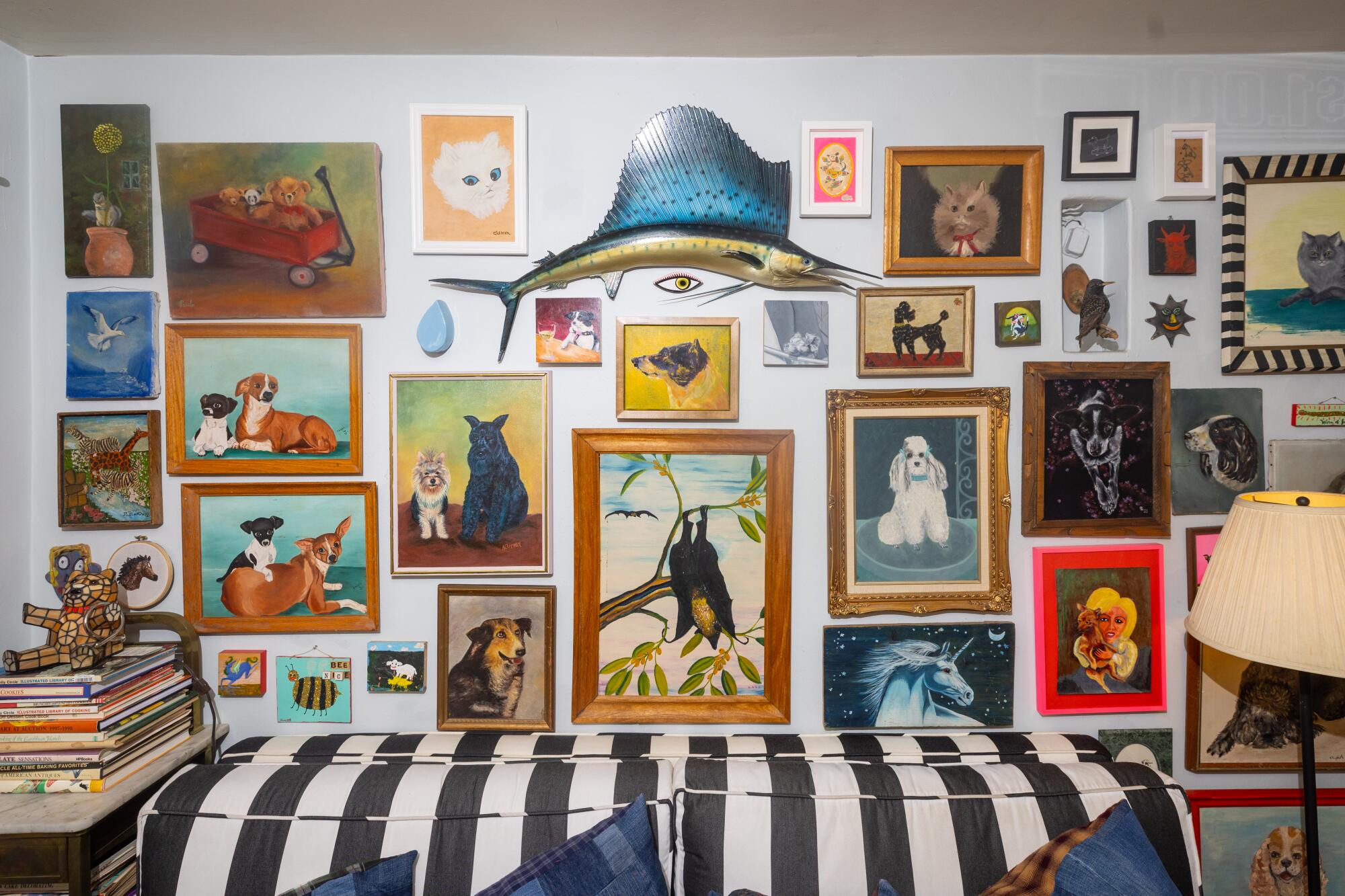 A black-and-white couch below colorful gallery wall of art.