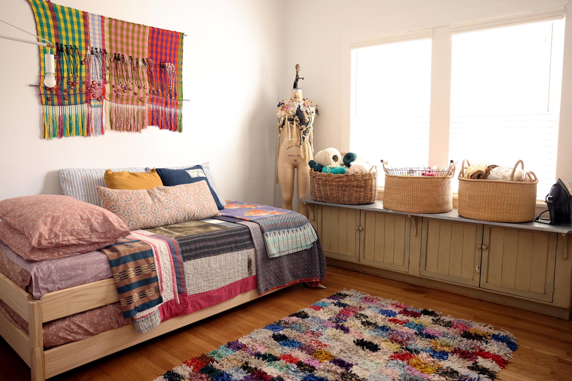 A guest room filled with textiles and baskets of yarn and crafts.