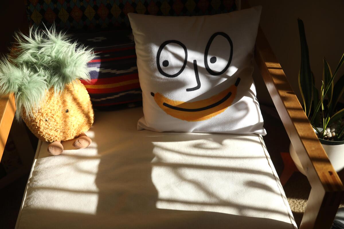 A smiling pillow and stuffed pineapple add to the quirkiness of the Betrans' apartment.