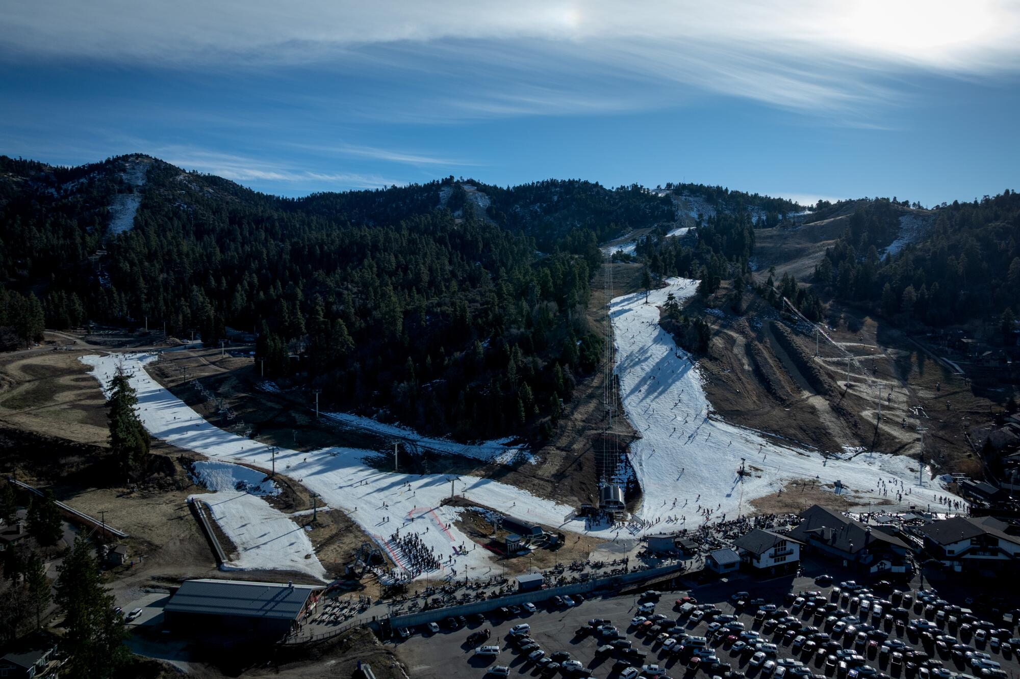 People ski and snowboard at Big Bear Mountain Resort on man-made snow surrounded by bare ground.