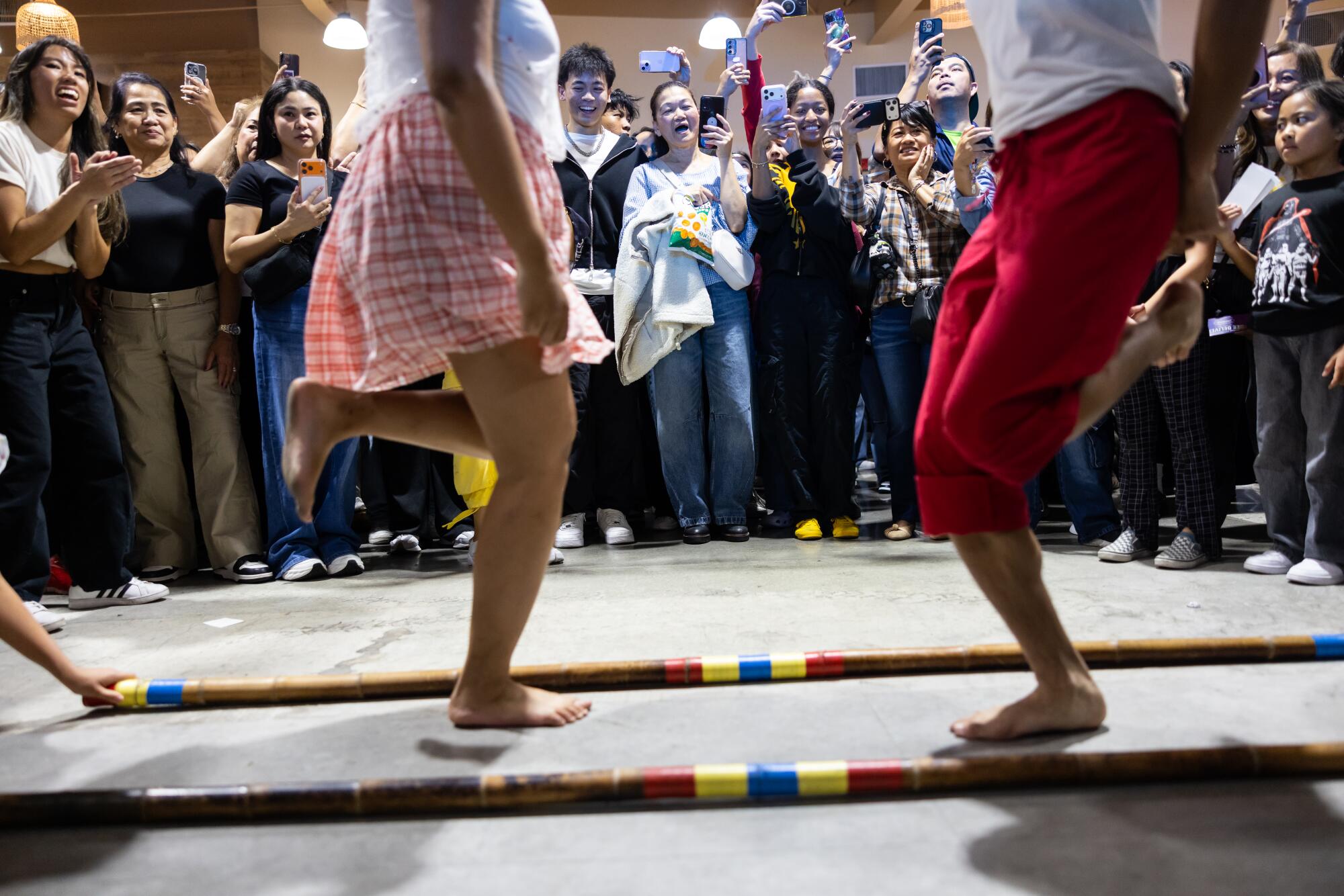 Dancers perform between bamboo staffs.