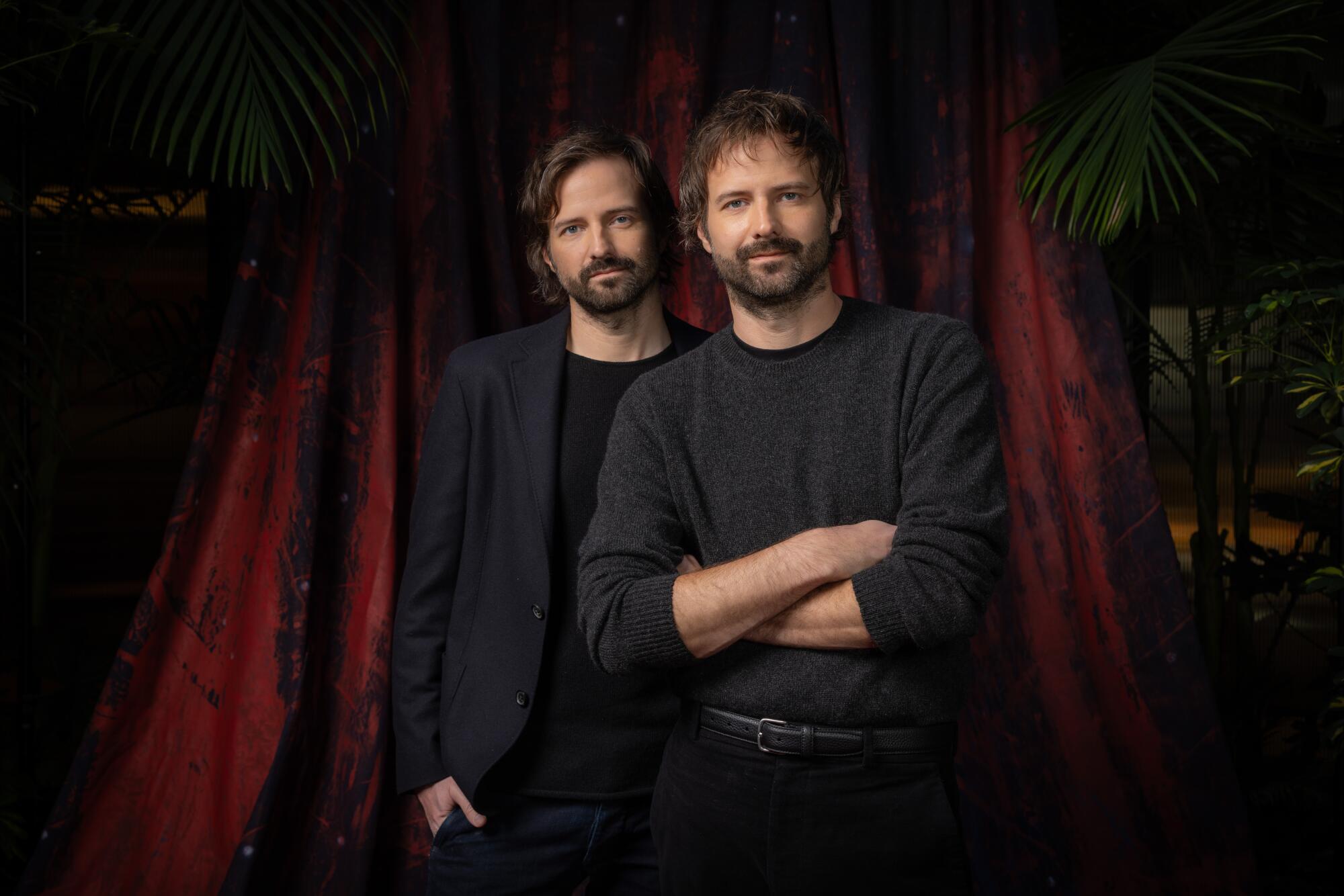 Two men posing for a photo against a red-and-black backdrop