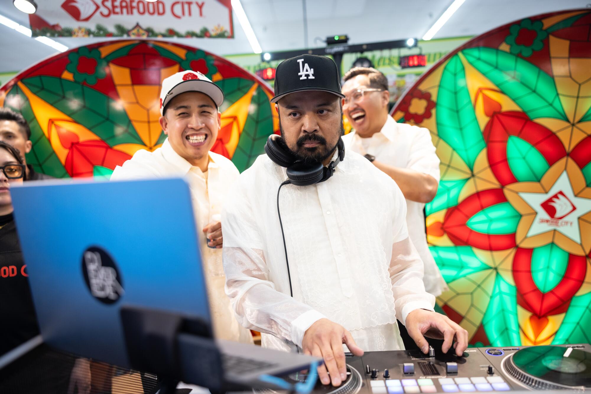 Two men smiling gather behind a man in front of a laptop.