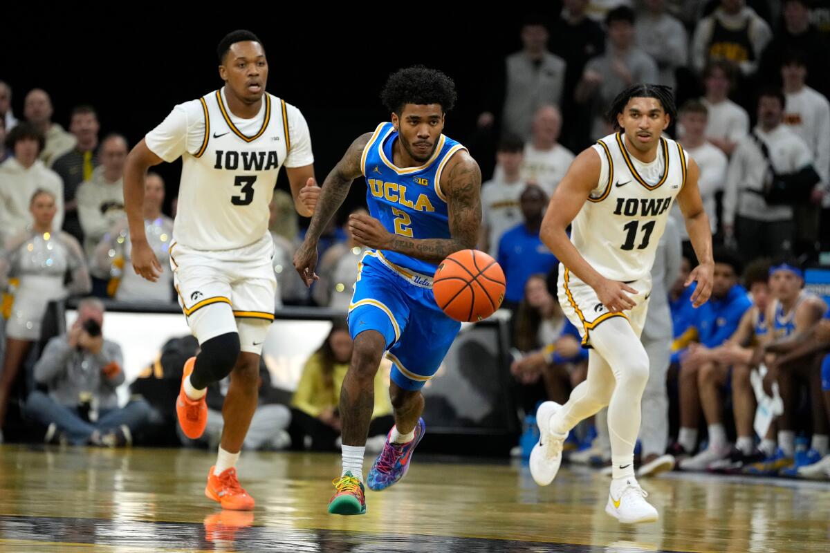 UCLA guard Donovan Dent chases after the ball in front of Iowa's Cam Manyawu and Kael Combs.