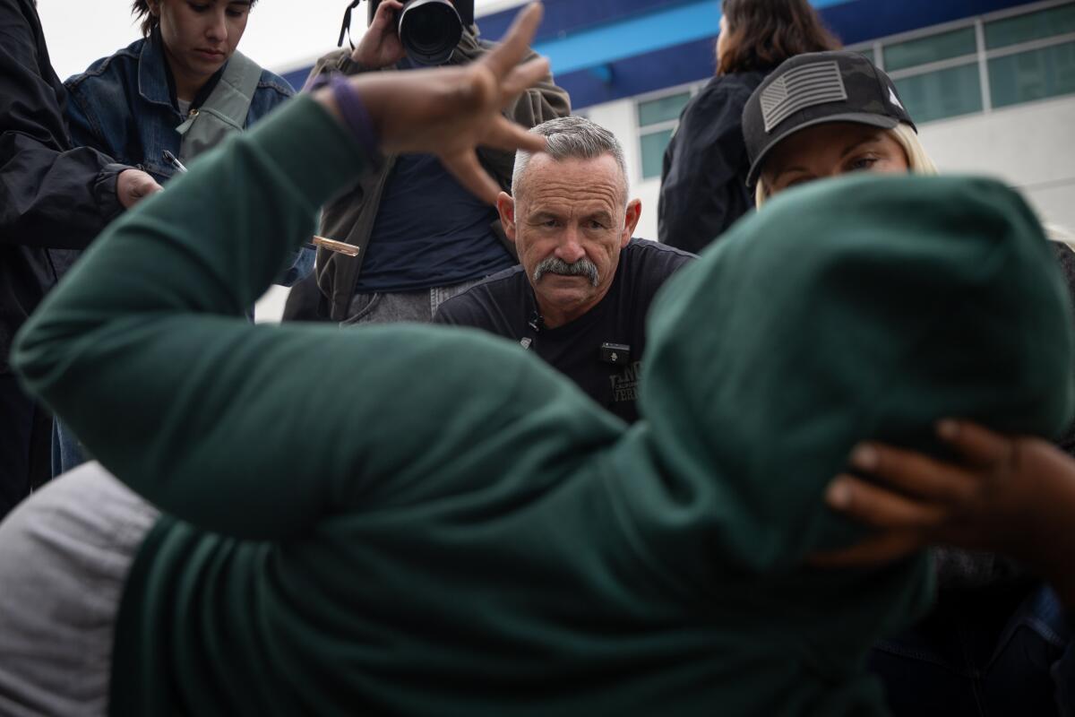 Two people talk to a person lying on the ground.